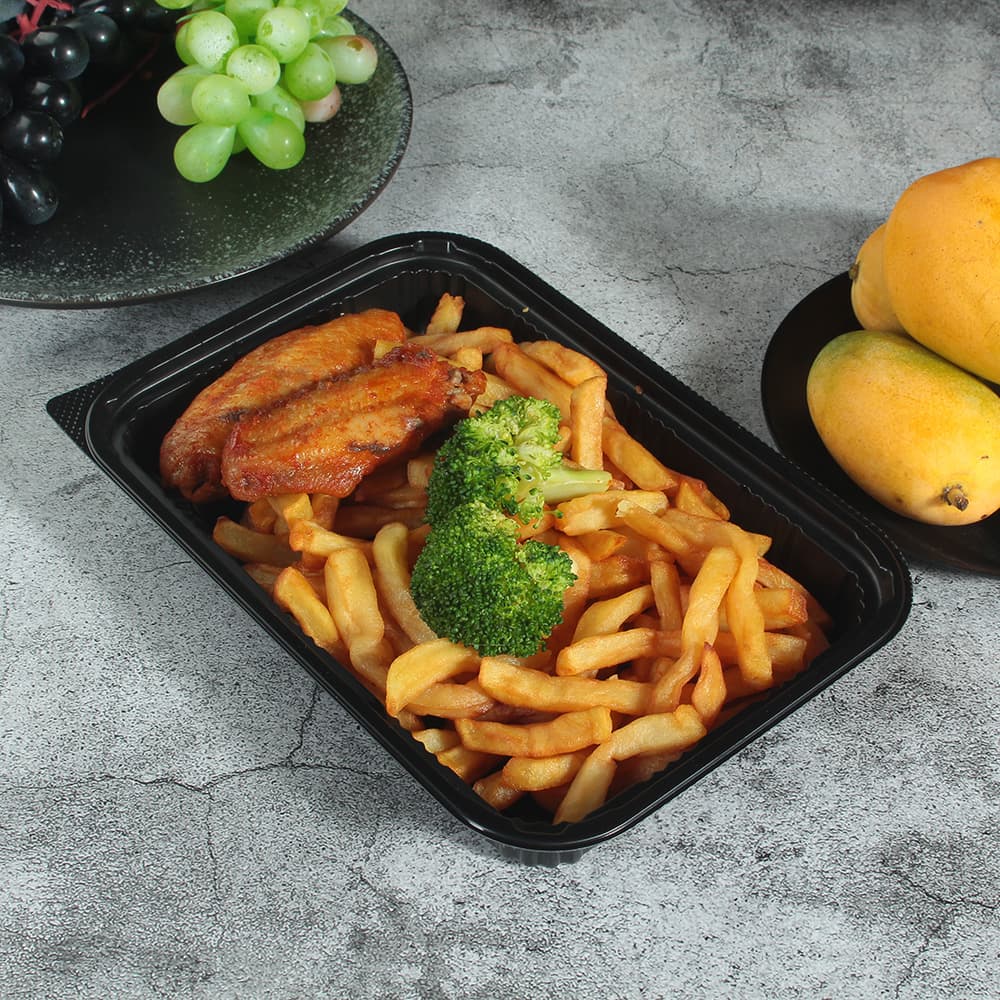 A black plastic takeout box contains fried chicken nuggets and french fries.
