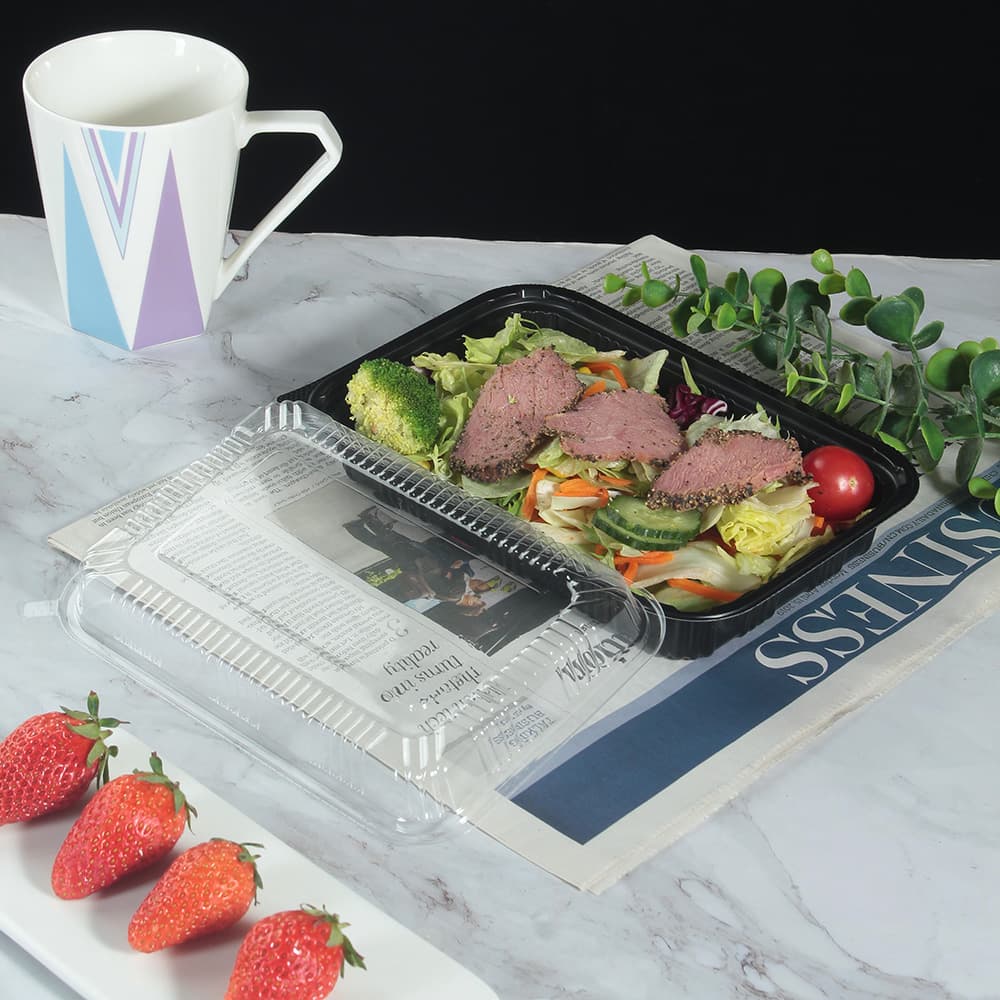 A black plastic lunch box filled with sliced meat and vegetables