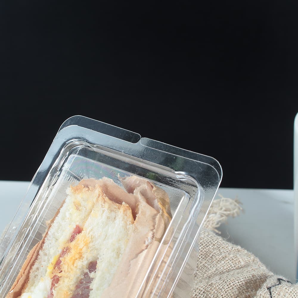 Lid lock detail of a clear clamshell container holding sandwiches