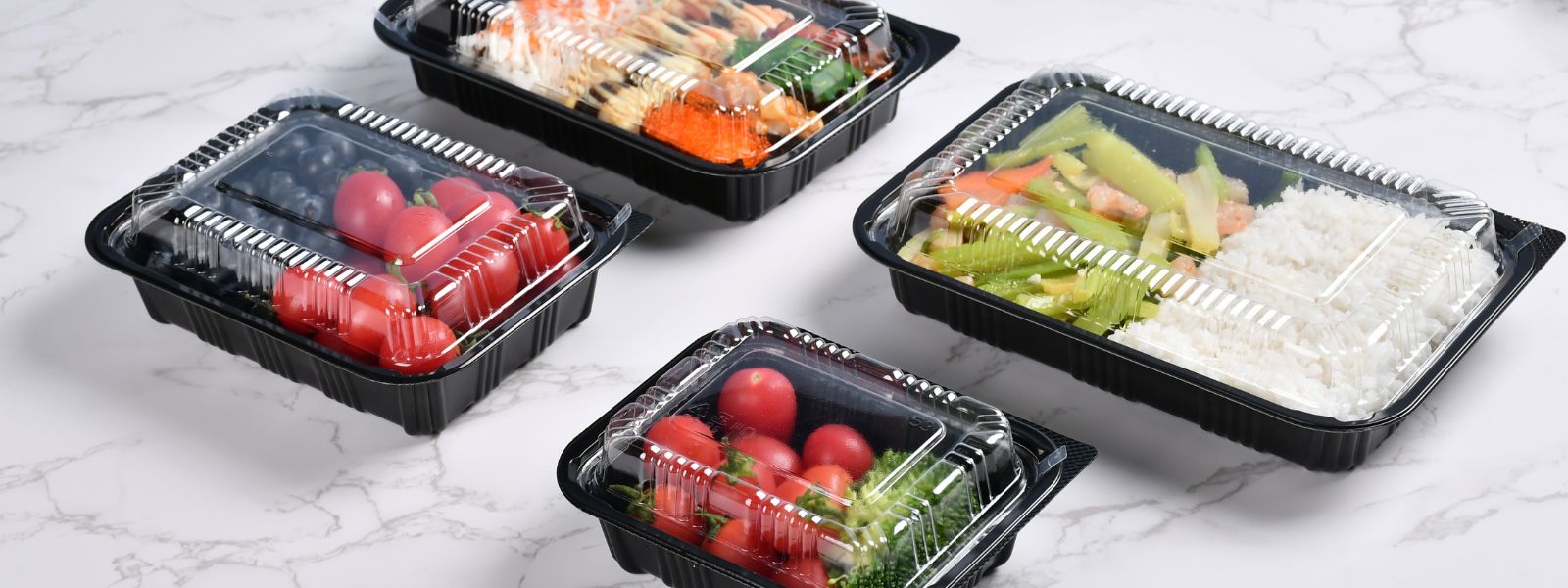 4 bento boxes of different sizes with sushi, fruit food placed together