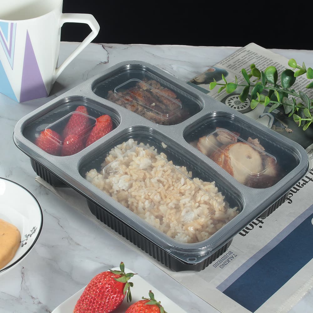 A 4-compartment lunch box with food is placed on the table
