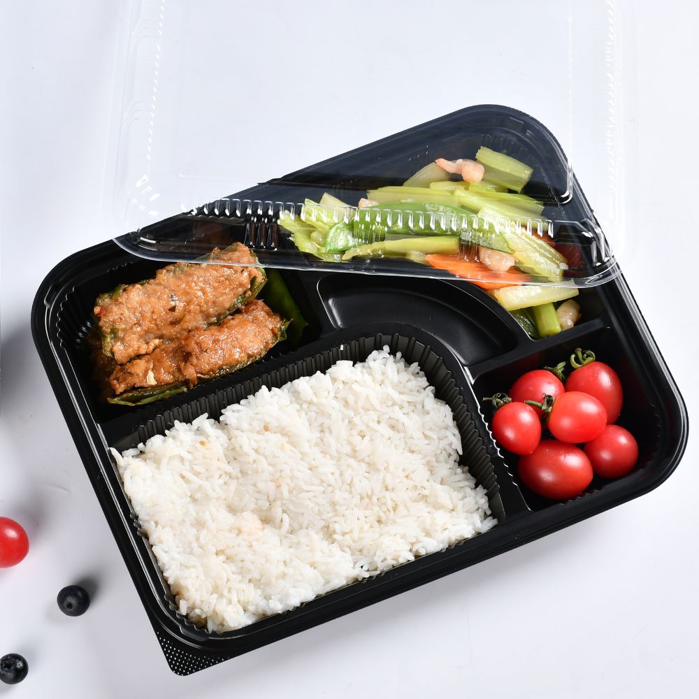 A black 5-compartment bento box with the lid half opened and each containing vegetables, fruits, meat slices and rice