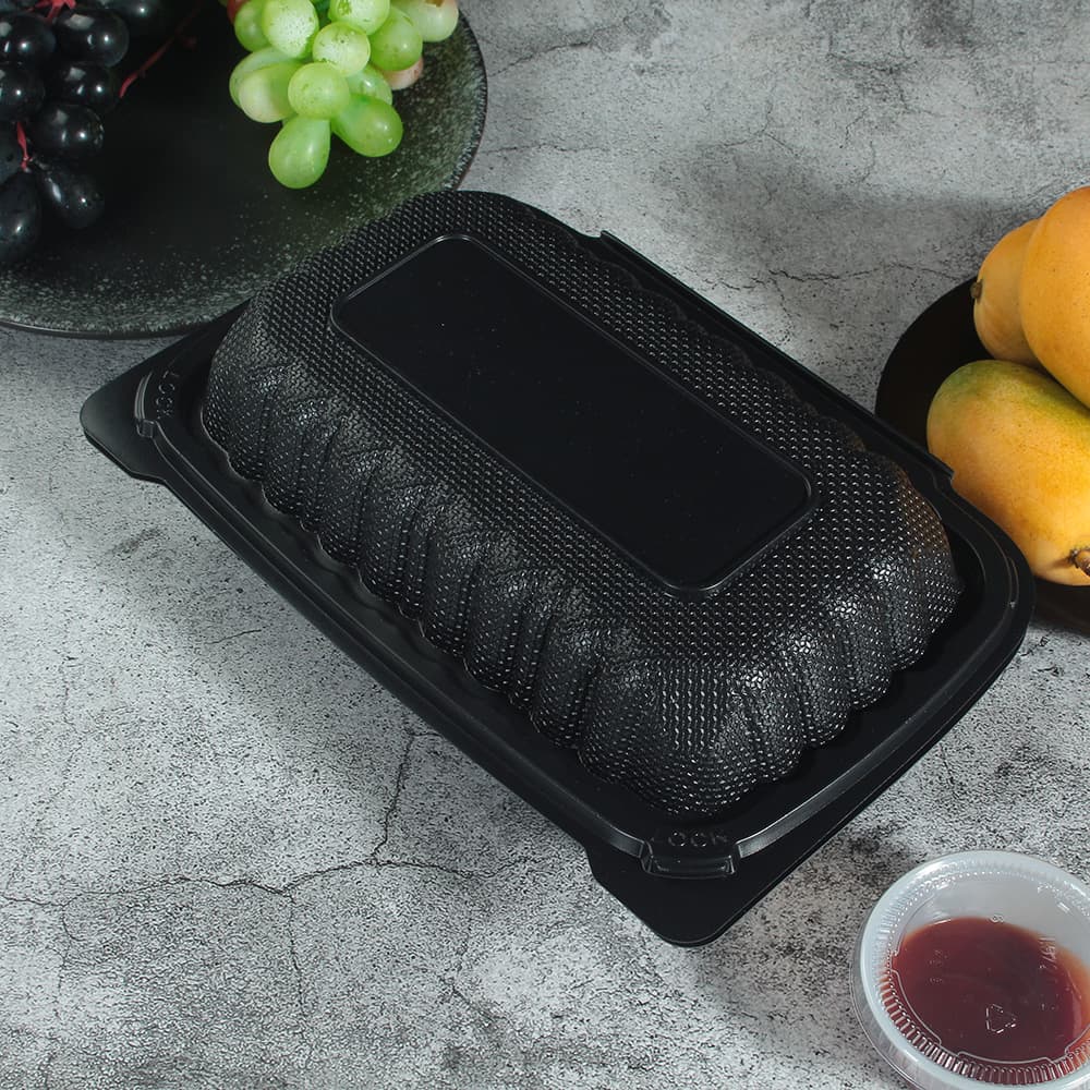 A black plastic clamshell container with a closed lid lies on the table