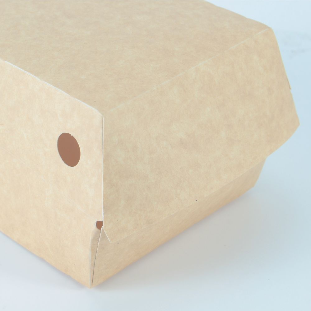 The closure detail of a kraft paper clamshell storage container that is closed and has a small circular ventilation hole next to it