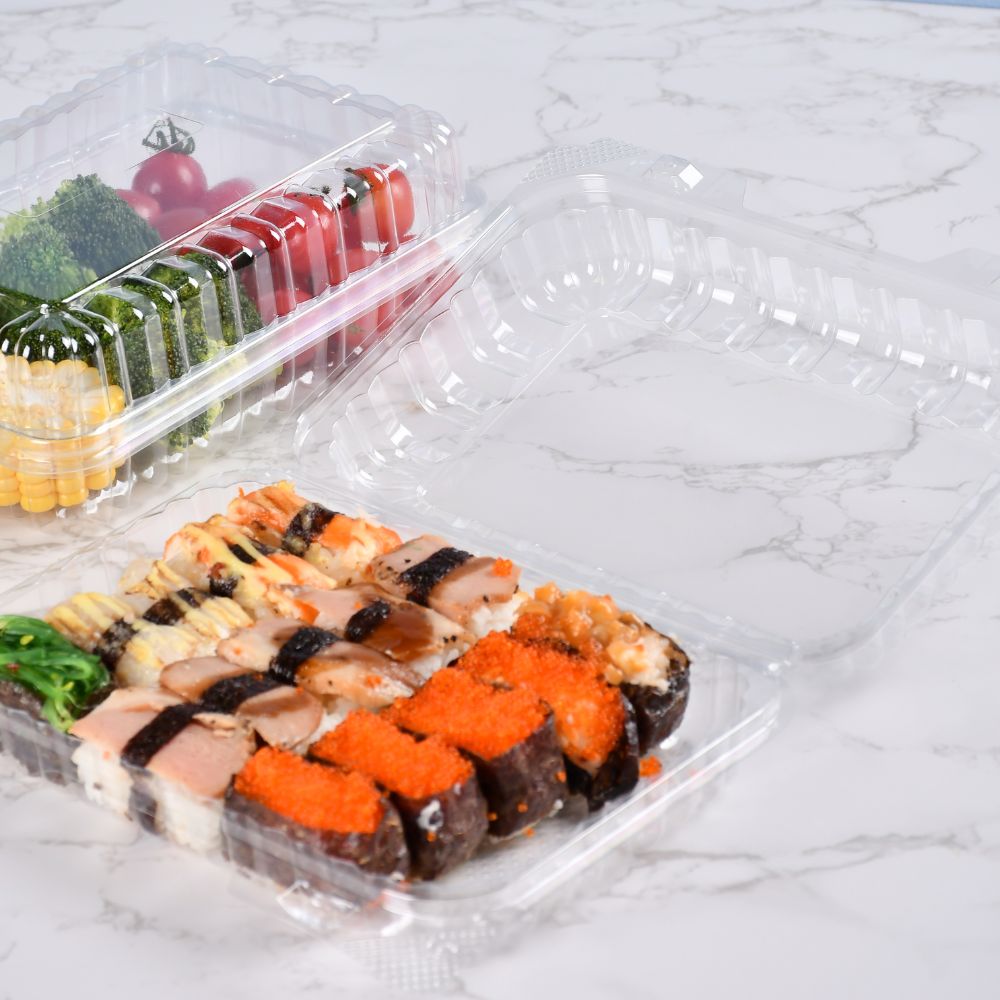 2 clear clamshell containers of different sizes containing corn, broccoli, cherry tomatoes and sushi on a light gray table
