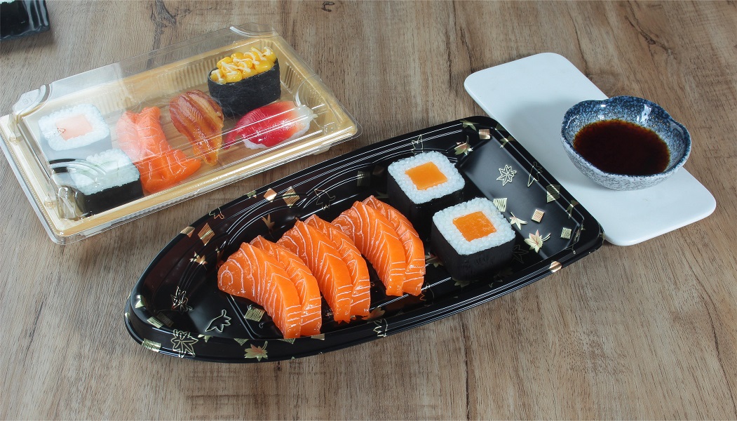 A black maple leaf print plastic boat-shaped sushi box without lid contains 2 pieces of sushi box with 6 pieces of salmon, and a plastic wood grain rectangular sushi box with lid contains 6 pieces of sushi and is placed on the table. There is also sushi vinegar on the table.