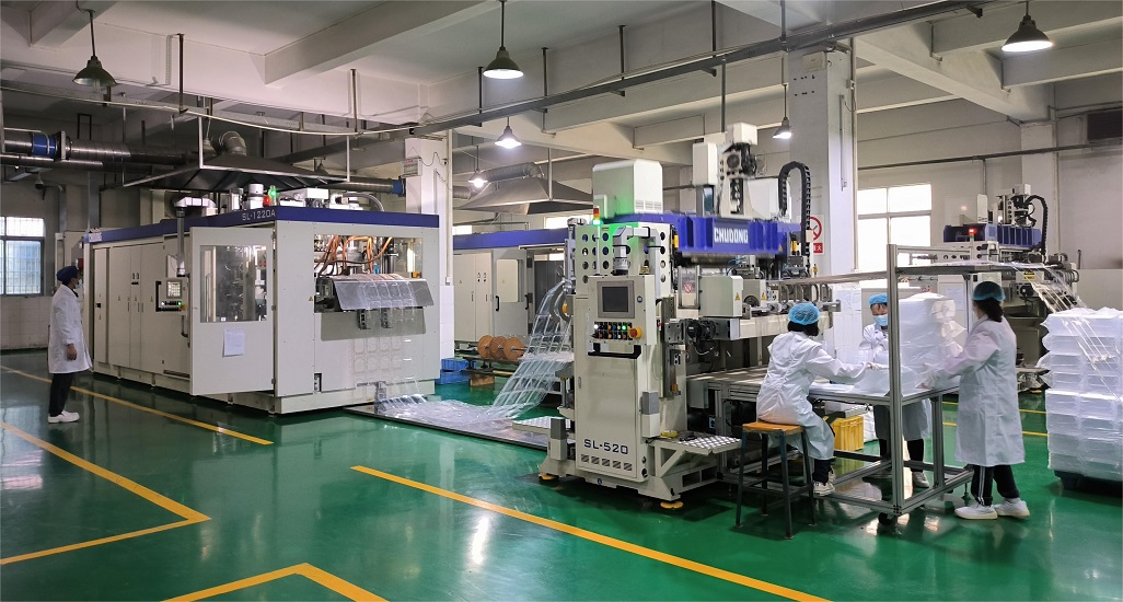 In a packaging production workshop, there are individuals wearing white clothes managing production machinery and testing products.