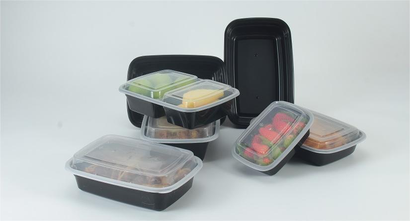 7 Meal Prep Containers of different sizes are placed on a gray background. Two of them are standing upright without food, and the other five lying flat or stacked contain different fruits and other food.