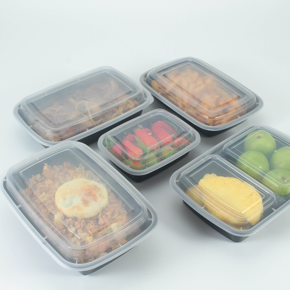 6 disposable black plastic food containers of different sizes are placed on a gray background with fruits, noodles and rice.