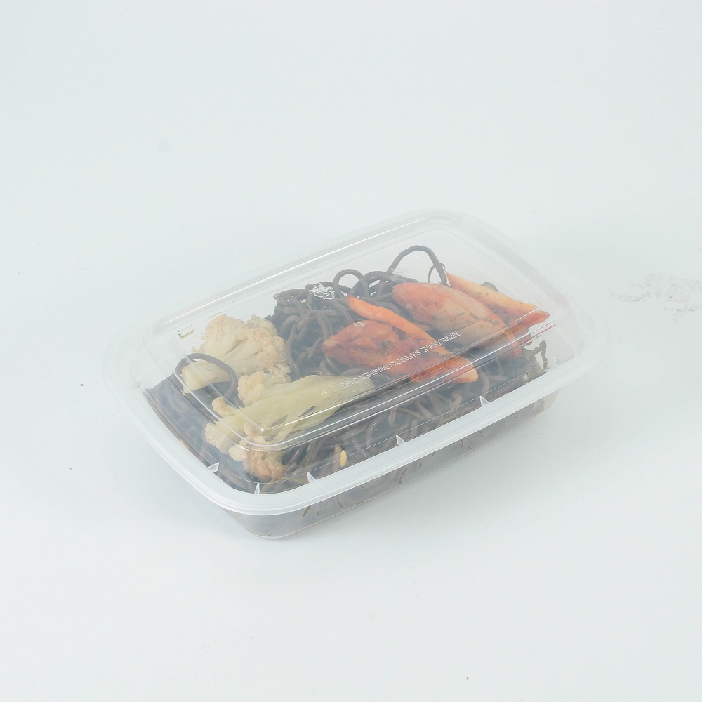 A transparent disposable plastic bento box with black noodles, meat, and vegetables on a gray background