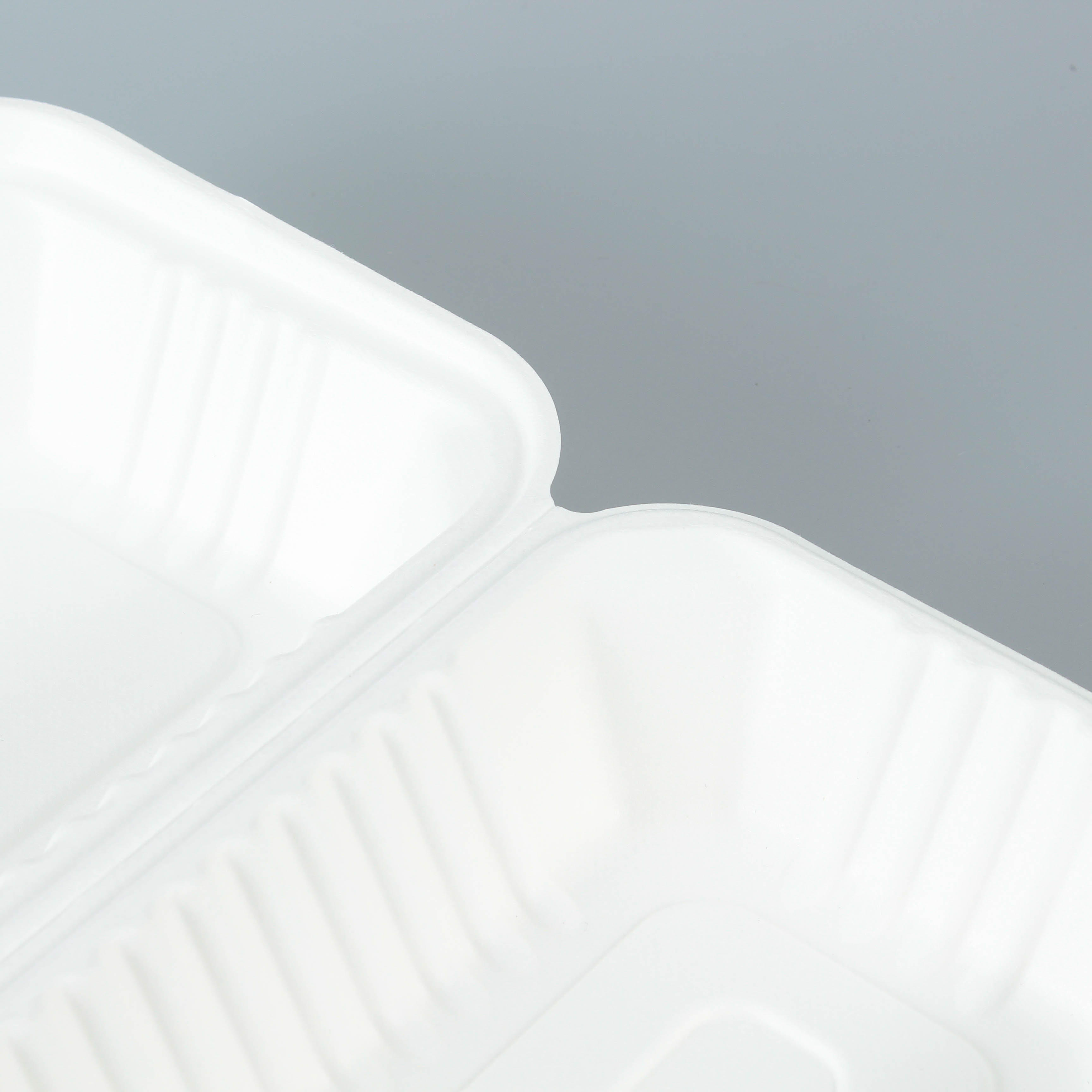 Details of the folds and edges of a white bagasse rectangular clamshell container, with a gray background